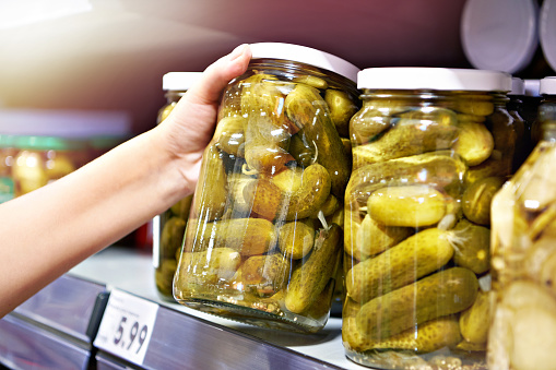 Canned pickles in hands in store