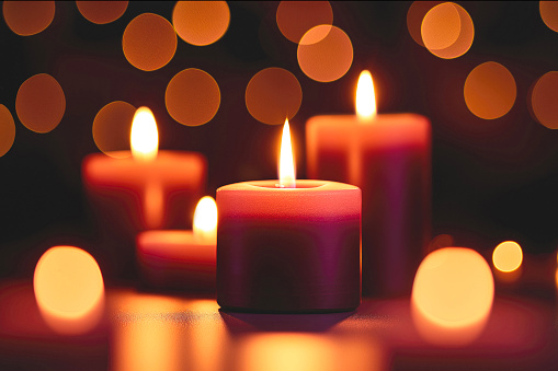 First Advent - decorated Advent wreath from fir branches with red burning candles on a wooden table in the time before Christmas, festive bokeh in the warm dark background, copy space, selected focus