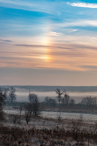 A parhelion in the sky (plural parhelia) - atmospheric optical phenomenon that consists of a bright spot to one or both sides of the Sun. This phenomenon also has names: sun dog (or sundog) or mock sun, also called. Morning landscape in the countryside