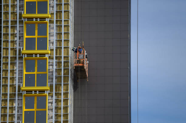 los trabajadores recubren las paredes exteriores del edificio con aislamiento. aislamiento de la fachada del edificio. acabado exterior - recubrimiento capa exterior fotografías e imágenes de stock