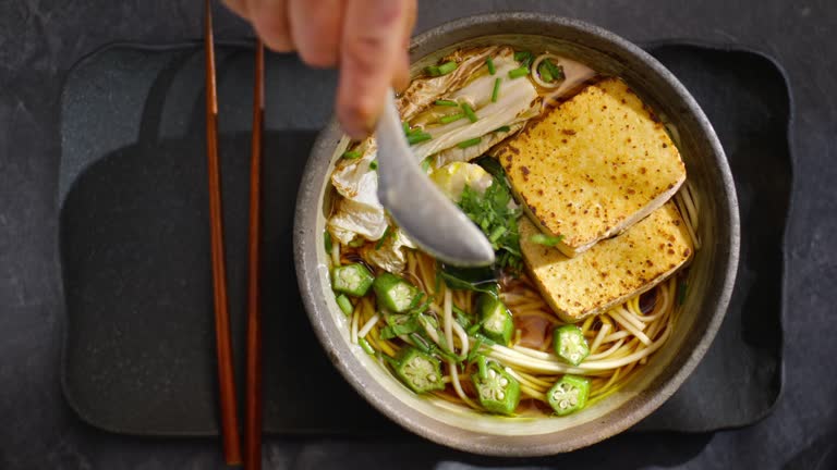 LD Person using a spoon to add fresh herbs to a bowl of miso soup