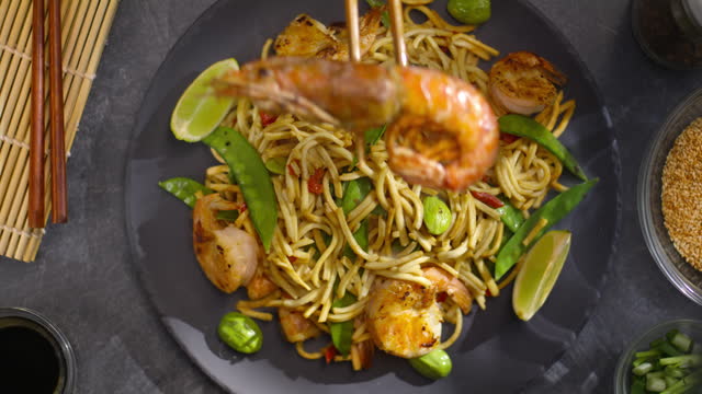 LD Person placing a prawn on top of stir fried noodles