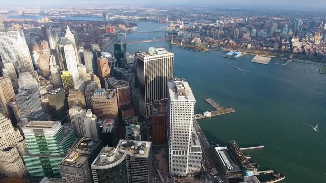 A high-flying, 4K drone shot over lower Manhattan, New York City, including the Freedom tower and the World Trade Center. The camera slowly moves forward toward the East River and the Brooklyn Bridge.