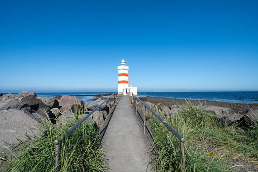 Gardur Old Lighthouse in Iceland, white and red striped light house on a sunny day