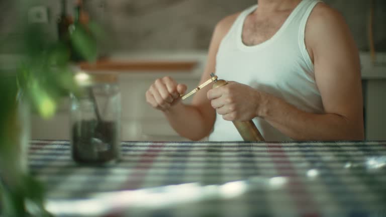 Man grinding roasted coffee beans with manual grinder at home