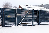 A modern gate with a letterbox and a wireless card reader, mounted in an anthracite panel fence, covered with snow.