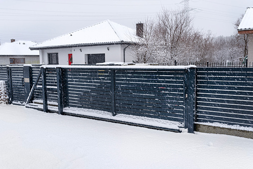 Modern anthracite panel fence with falling smeared snow during a snowstorm.