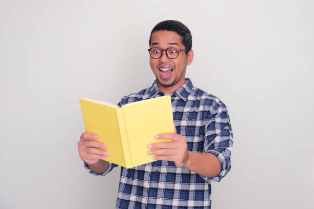 istock Adult Asian man looking to book that he hold with wow expression 1887368995