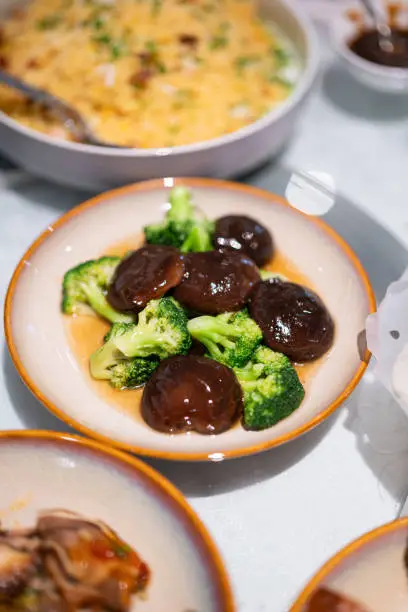 Shiitake mushroom mixed broccoli vegetable stir-fired with oyster sauce, Chinese food menu that served in ceramic dish. Food object photo, close-up.