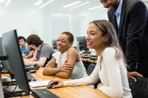 istock Two female college students smile as professor supervises work 1887375722