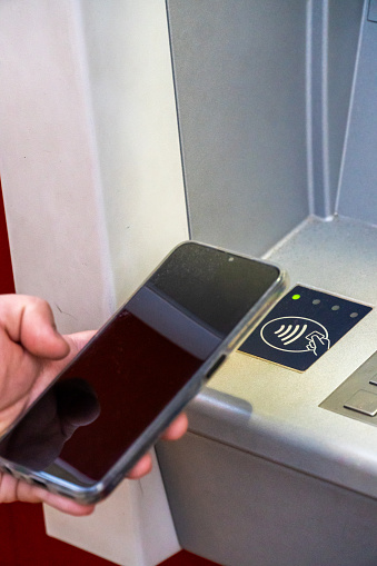 Person connects via NFC the smartphone with the ATM