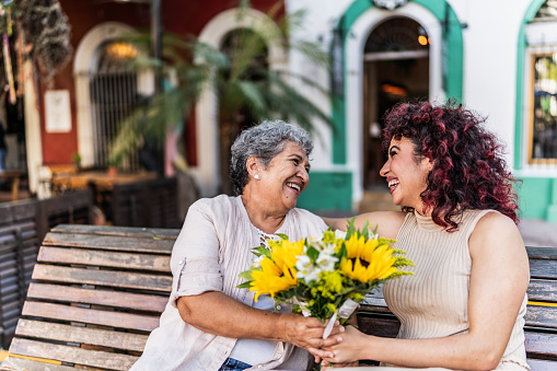 Grandmother receiving a bouquet of flowers from her granddaughter outdoors