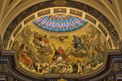A view looking up at the painted Christian artwork and stained glass in the ceiling of  the Basilica of St. Josaphat in Milwaukee, Wisconsin.