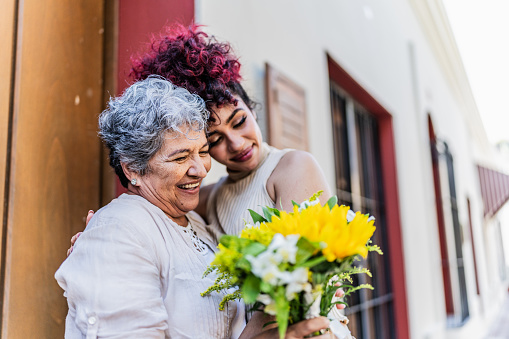 Grandmother receiving a bouquet of flowers from her granddaughter outdoors