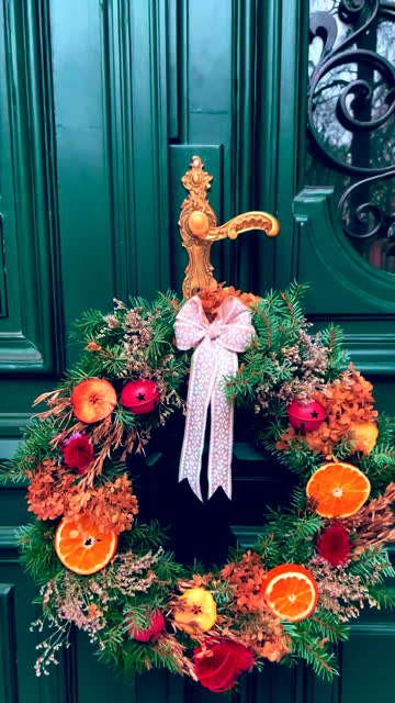 Christmas orange fruit decor wreath on a green door.