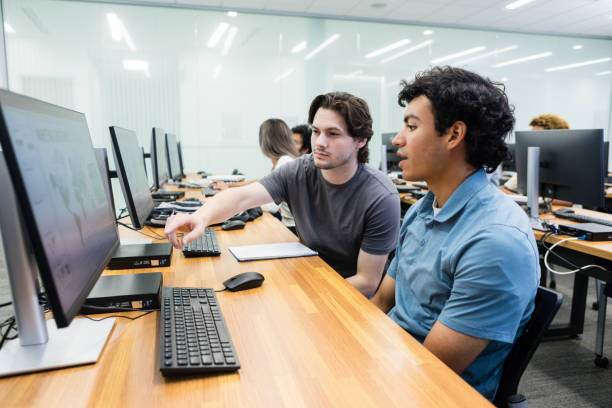 istock Young adult male helps train his peer on a new software 1887420407