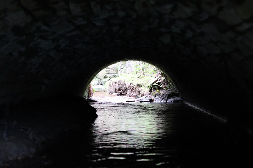 View through a tunnel carrying a stream beneath a road