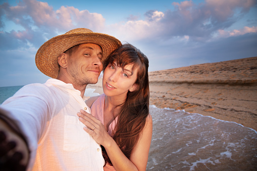 Close up smiling happy young couple two family man woman in casual clothes hug each other doing selfie shot pov on mobile phone. at sunrise over sea beach outdoor seaside in summer day sunset evening.