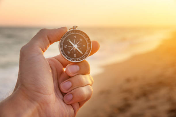 ręka mężczyzny trzyma kompas na plaży. ręka z kompasem nad piaskiem nad morzem, kierunek i koncepcja przygody - compass exploration the way forward beach zdjęcia i obrazy z banku zdjęć