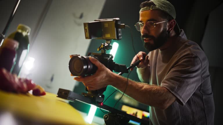 Slow Motion Shot of Male Cinematographer Working On a Filming Set, Using Digital Camera to Shoot Table top Footage for Cinematic Project. Creative Man Operating a Camera To Film Macro Shots