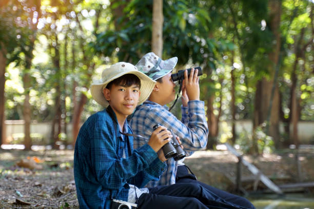 istock Asian boys use binoculars to look at birds in a community forest own. 1887438564