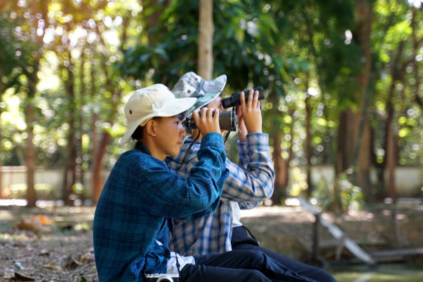 istock Asian boys use binoculars to look at birds in a community forest own. 1887438687