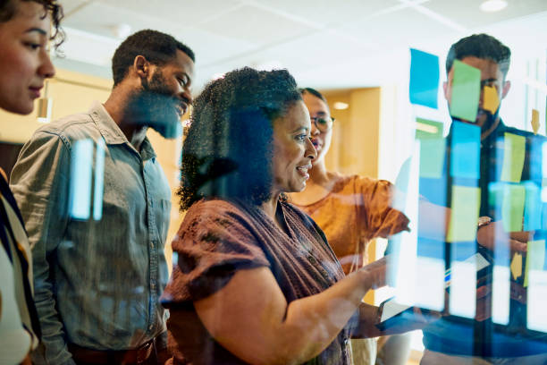 istock Diverse Professionals Brainstorming on Glass Wall in Modern Office 1887444242