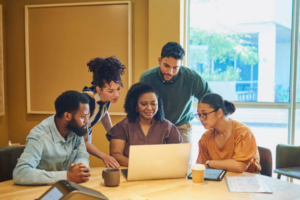 Diverse Colleagues Gathered Around Laptop In Modern Office