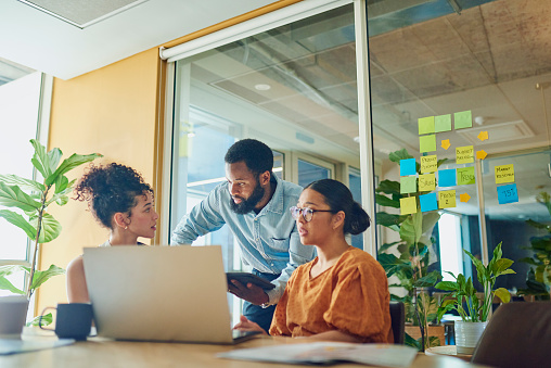 Three diverse professional women in business attire smiling and posing in an office