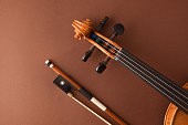 Peg box and fingerboard of violin and bow on brown