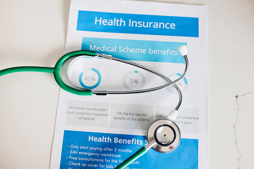 A stethoscope rests on a document titled 'Health Insurance'.