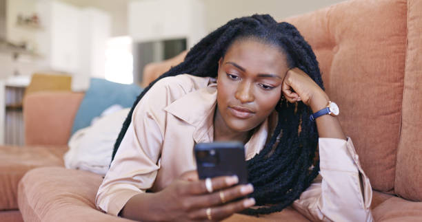istock Young woman relaxing on couch and using smartphone 1887469769