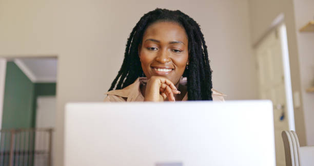 istock Young black woman smiling while looking at her laptop screen. 1887470310