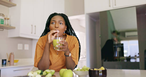 istock Young Woman Drinking a Green Smoothie in the Kitchen 1887470337