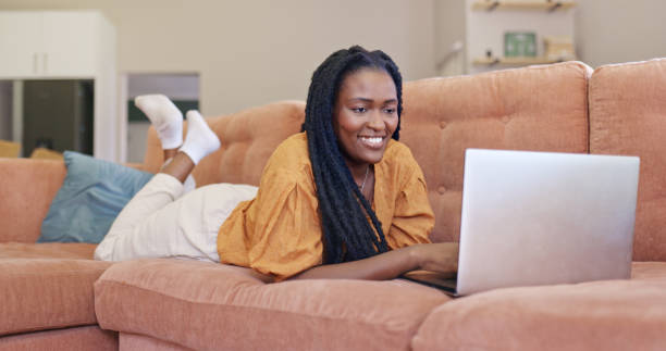 istock Young woman lying on couch and using laptop. 1887470876