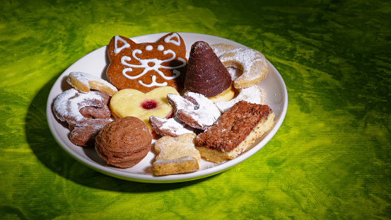 Czech Christmas cookies cukrovi on white plate on green background