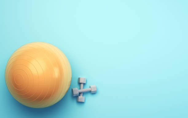 Yellow Pilates Ball and Gray Dumbbell Set on Blue Soft Background
