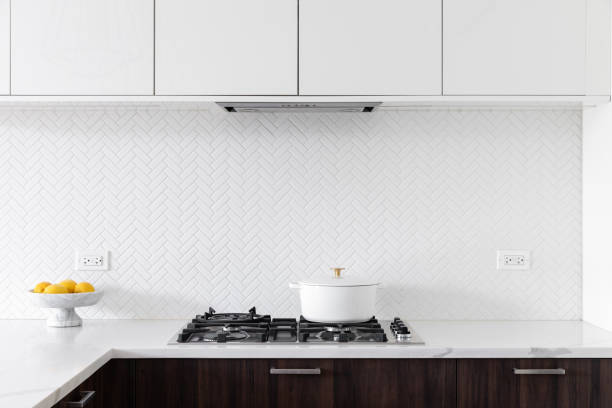 istock A kitchen detail with white and wood cabinets and a white herringbone backsplash. 1887529525