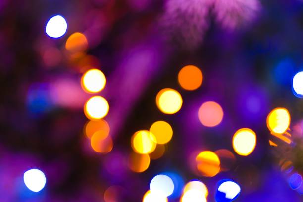 A mesmerizing image captures the enchanting glow of blurred lights on a Christmas tree, creating a warm and festive ambiance.