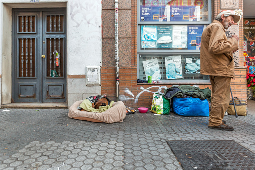 Seville, Spain - December 20, 2023: A homeless man and his dog on the street in Seville