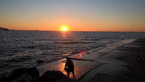 A man crouched watching sunset over the sea, Istanbul, Turkiye, Turkey