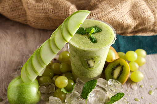 Mixed apple, kiwi and grapes smoothie served in disposable glass isolated on table side view of healthy drink