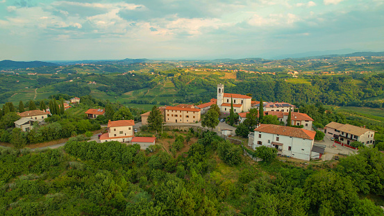 AERIAL: Picturesque settlement on top of small hill in embrace of wine country. Well-kept vineyards, forest patches and idyllic small settlements scattered across beautiful hilly landscape in autumn.