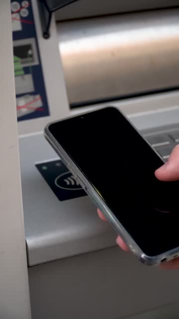 A person brings the phone closer to the ATM to connect via NFC