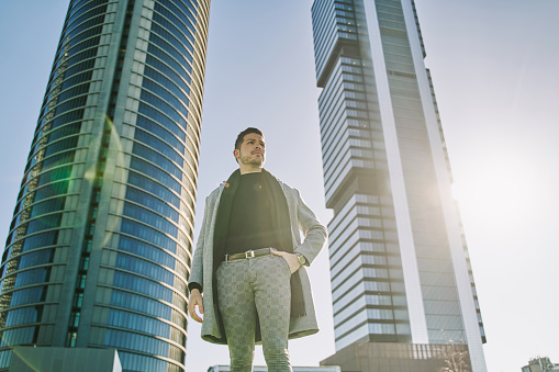 portrait of a young Latino businessman with office buildings in the background and copy space for text.