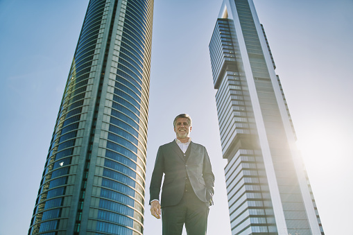 portrait of a mature businessman with office buildings in the background and copy space for text.