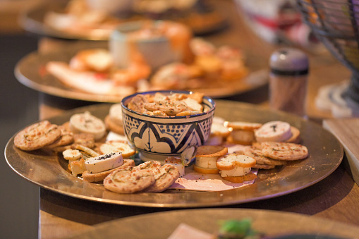 Gold Plates of hors d'oeuvre lined up on a wooden kitchen surface, party food, celebration event