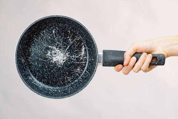Hand holding scratched frying pan