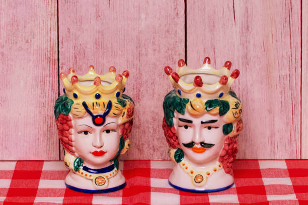 souvenir de sicilia. ollas o jarrones tradicionales de cerámica siciliana con cabezas de una pareja de amantes de las cabezas moriscas sobre servilleta de cuadros rojos de pared de madera. - heath ceramics fotografías e imágenes de stock