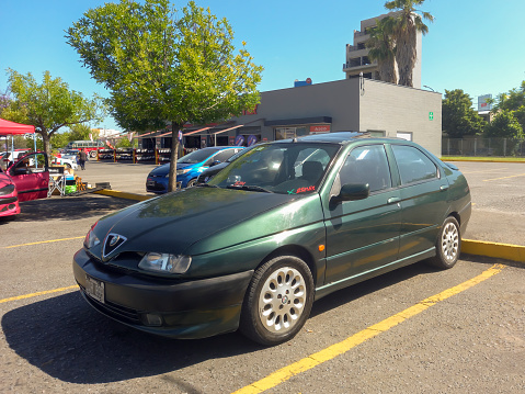Buenos Aires, Argentina - Dec 10, 2023: Old green shiny late 1990s Alfa Romeo 146 ti five door hatchback at a classic car show in a parking lot in a sunny day.